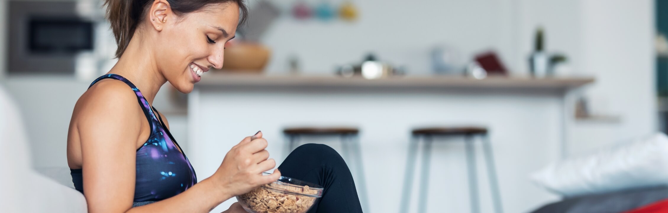 sporty-young-woman-eating-a-bowl-of-muesli-while-l-2022-12-15-18-19-12-utc-1